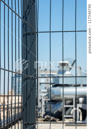 A close up of a metal fence with a building in the background on a city street A close up of a metal fence with a building in the background on a city street 117348740