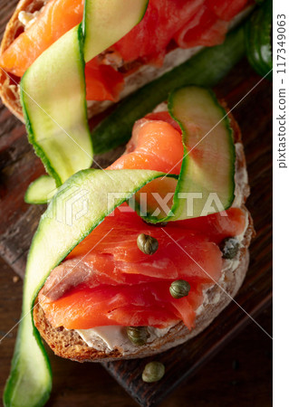 Sandwiches with smoked trout, cream cheese, fresh cucumber, and capers on a cutting board. Sandwiches with smoked trout, cream cheese, fresh cucumber, and capers on a cutting board. 117349063