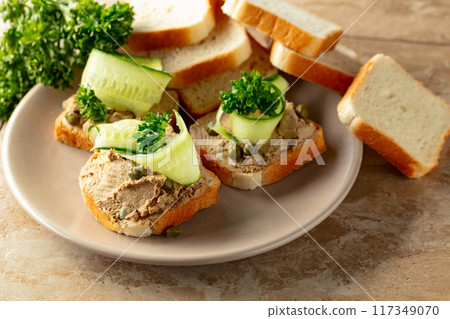 Open sandwiches with pate, cucumber, capers, and parsley. 117349070