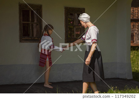 A woman and a little girl hold hands happily in front of a house A woman and a little girl hold hands happily in front of a house 117349202