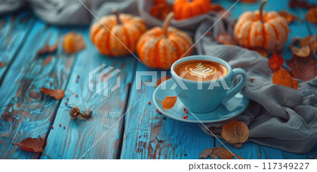 Blue coffee cup with hot drink on turquoise wooden table surrounded by small pumpkins, dried leaves, blue fabric in warm autumn light. Cozy fall morning with seasonal decorations. Ai generation 117349227