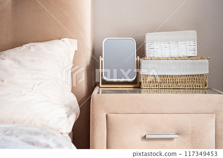 Minimalist bedroom nightstand with mirror and storage baskets. Minimalist bedroom nightstand with mirror and storage baskets. 117349453