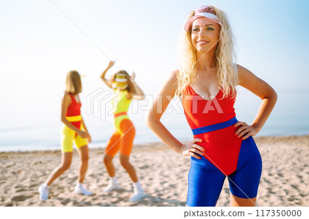 Three young woman - dancer dancing in bright swimsuits on the beach. Sport, fitness, active life. 117350000