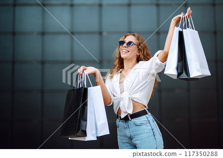 Young woman with shopping bags walking on street. Summer shopping. Sale, shopping, lifestyle concept Young woman with shopping bags walking on street. Summer shopping. Sale, shopping, lifestyle concept 117350288