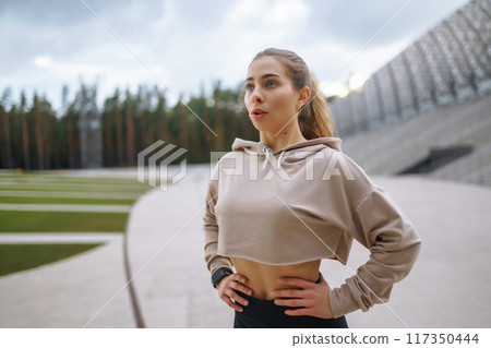 Young woman in sports outfit doing exercises outdoors in morning. Concept of sports, yoga or fitness 117350444