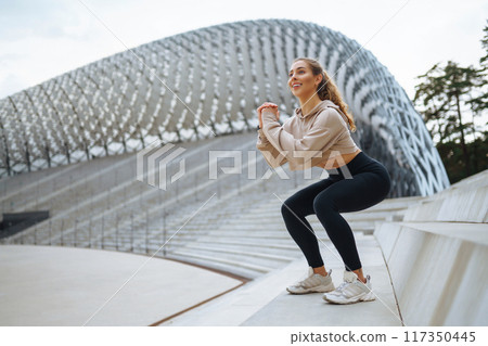 Young woman in sports outfit doing exercises outdoors in morning. Concept of sports, yoga or fitness 117350445