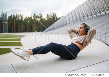 Young woman in sports outfit doing exercises outdoors in morning. Concept of sports, yoga or fitness 117350446