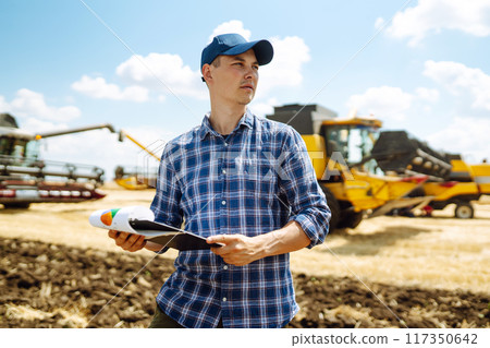 Farmer holds tablet with yield map for combine in wheat field. Precision farming Agriculture concept Farmer holds tablet with yield map for combine in wheat field. Precision farming Agriculture concept 117350642