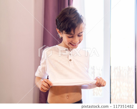 Young boy dressing up in bedroom Young boy dressing up in bedroom 117351482