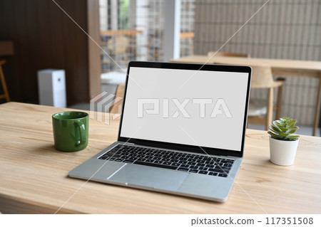 Laptop computer blank white screen and cup of coffee on wooden table in modern office 117351508