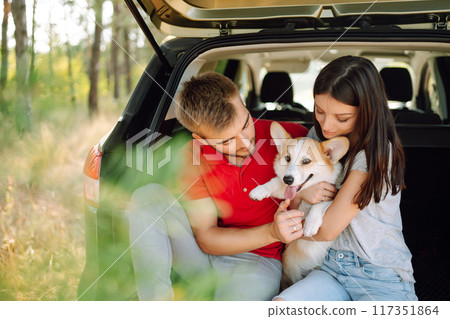Portrait of caring, loving couple with their dog in back seat of car while traveling. Pet and human. 117351864
