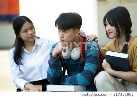 Friends comforting stressed student on campus 117351902