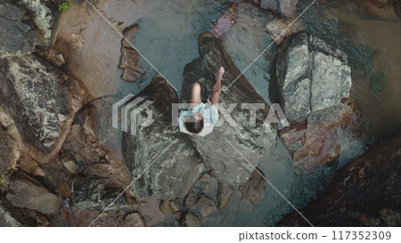 Relaxing woman on rocks in thailand's shallow waters, captured by drone, showing harmony of zen-like lifestyle. Explore peaceful moments in tropical paradise 117352309