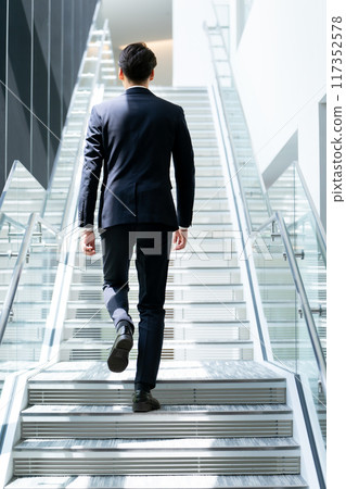 K businessman climbing the stairs 117352578