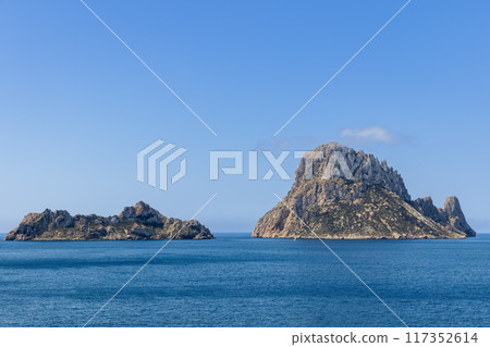 Es Vedra and Es Vedranell islands in Ibiza with cliffs rising from the calm Mediterranean Sea 117352614