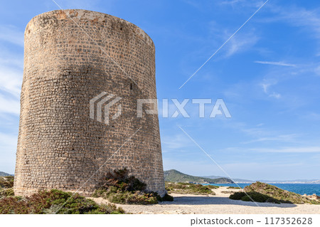 Torre de ses Portes on Ibiza, an old stone tower set against blue sky, overlooking Mediterranean Sea Torre de ses Portes on Ibiza, an old stone tower set against blue sky, overlooking Mediterranean Sea 117352628