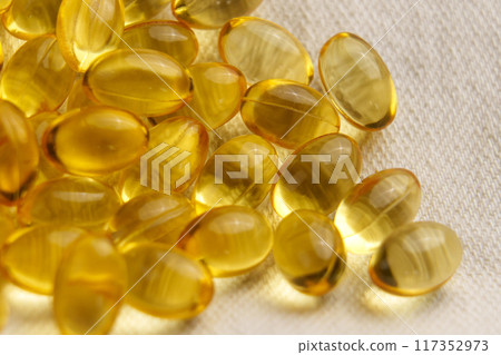 Golden soft gel capsules on a textile background. Nutritious diet vitamin pills Golden soft gel capsules on a textile background. Nutritious diet vitamin pills 117352973