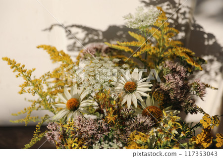 Summer meadow and garden flowers still life in sunset light. Closeup of yellow, pink and white floral bouquet in sunlight. Solidago, echinacea. Eupatorium flowers. Selective focus, blurred background 117353043