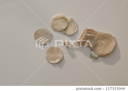 Bio organic cotton reusable round pads for make up removal and string bag in sunlight isolated on beige table background. Zero waste concept. Sustainable bathroom and lifestyle. Flat lay, top view. Bio organic cotton reusable round pads for make up removal and string bag in sunlight isolated on beige table background. Zero waste concept. Sustainable bathroom and lifestyle. Flat lay, top view. 117353044