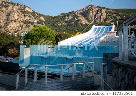 Water Slide Park Mountain - A large water slide in a park with mountains in the background. 117353561