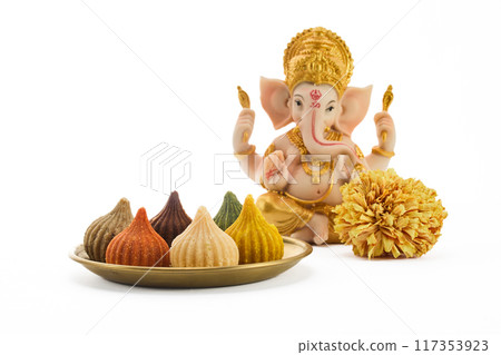 Ganesh Chaturthi Festival. Ganesha idol with colorful Modaks on a white plate. Ganesh Chaturthi Festival. Ganesha idol with colorful Modaks on a white plate. 117353923