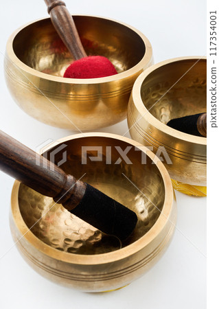 Tibetan Singing Bowls. Three Tibetan singing bowls with wooden mallets on a white background. 117354001