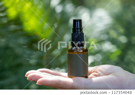 Spray Bottle on Open Hand in Natural Setting 117354048