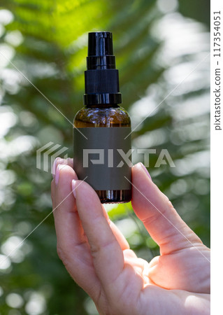Spray Bottle in Hand Amidst Lush Greenery Spray Bottle in Hand Amidst Lush Greenery 117354051