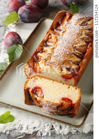 Delicate sponge cake with plums and yogurt close-up in a plate. Vertical 117354124