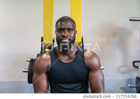 Black personal trainer smiling during gym workout 117354266
