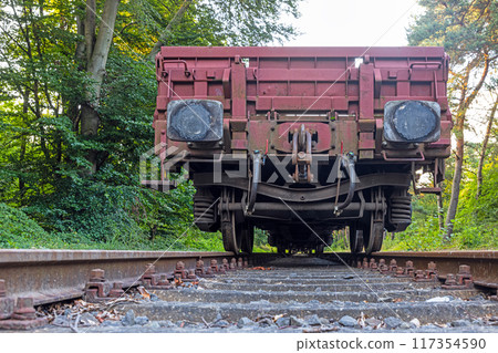 Picture of an cargo railroad car standing on a track photographed from the ground perspective 117354590