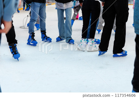 Close-up bottom people group wearing ice skates on outdoor ice skating rink city market park square. Christmas winter seasonal social and recreational atmosphere of holidays family outside activities Close-up bottom people group wearing ice skates on outdoor ice skating rink city market park square. Christmas winter seasonal social and recreational atmosphere of holidays family outside activities 117354606