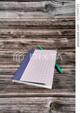 Notepad with crossed and parallel lines along with a pencil on a wooden desk.  117354731