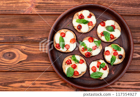 Italian mini pizza . Aubergine (eggplant ) with mozzarella cheese and basil . On rustic background 117354927