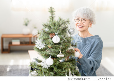 裝飾聖誕樹裝飾品的高級婦女 裝飾聖誕樹裝飾品的高級婦女 117355162