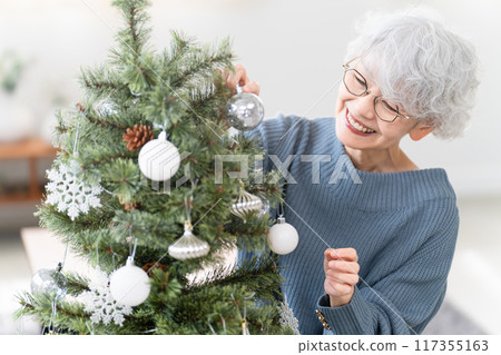 Senior woman decorating Christmas tree with ornaments Senior woman decorating Christmas tree with ornaments 117355163