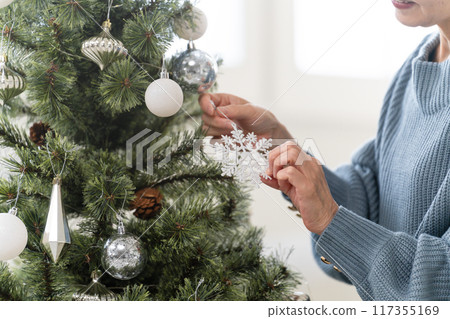 Senior woman decorating Christmas tree with ornaments Senior woman decorating Christmas tree with ornaments 117355169
