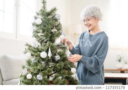 Senior woman decorating Christmas tree with ornaments Senior woman decorating Christmas tree with ornaments 117355170