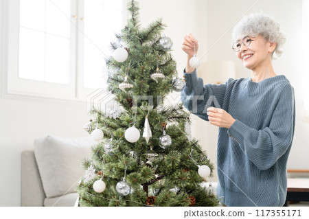 Senior woman decorating Christmas tree with ornaments Senior woman decorating Christmas tree with ornaments 117355171