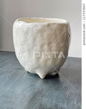 White glaze ceramic pot with craquelure. Empty flowerpot on blue background 117355607