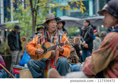 Street performers captivate a diverse crowd with live music in a vibrant city setting 117356472
