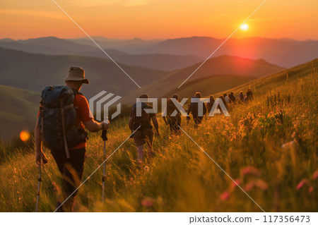 Group of hikers embarking on an early morning guided hike, surrounded by a golden sunrise over the hills 117356473