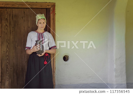 A Traditional Woman in a Beautiful Folk Costume Holding a Decorative Pot in Her Hands 117356545