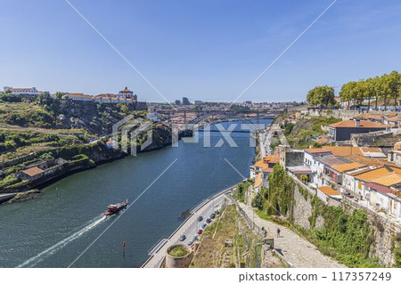 a river running through the middle of a city next to a forest 117357249