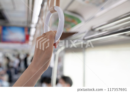 Woman's hand holding onto a strap 117357691