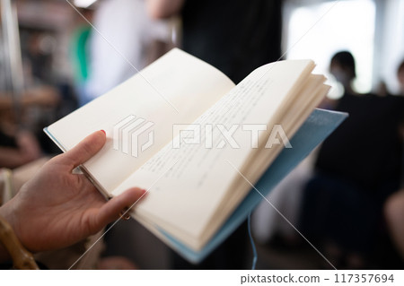 Hands of a woman reading a book on a train Hands of a woman reading a book on a train 117357694