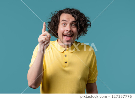 Brainy man having idea eureka moment, pointing finger up on blue.Solution,answer Brainy man having idea eureka moment, pointing finger up on blue.Solution,answer 117357776