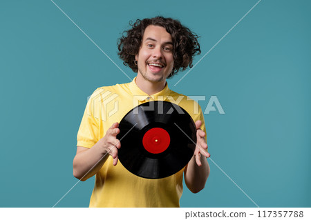 Happy curly man with vinyl record disc on blue. Hobby, music lover, collection 117357788
