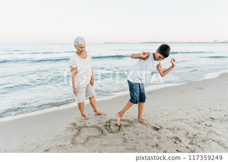 summer vacation at sea. Boy and senior woman at seaside. Grandmother with grandchild are resting on sea, running on beach having fun at summer holiday. Active parents, people activity with children. summer vacation at sea. Boy and senior woman at seaside. Grandmother with grandchild are resting on sea, running on beach having fun at summer holiday. Active parents, people activity with children. 117359249