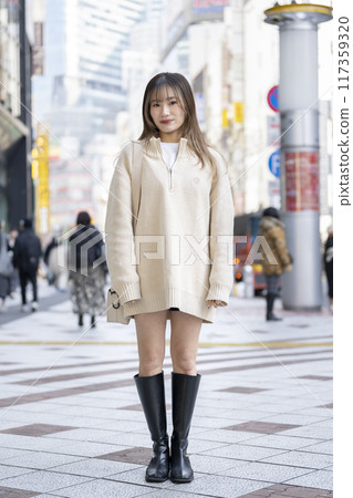 A woman in her 20s wearing a knitted dress and smiling at the camera A woman in her 20s wearing a knitted dress and smiling at the camera 117359320